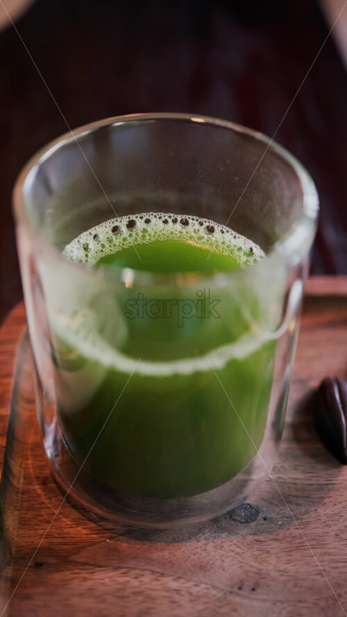 Close up of a glass of green tea on a table. Vertical - Starpik Stock