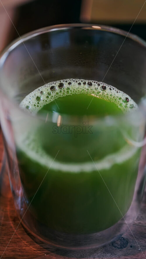 Close up of a glass of green tea on a table. Vertical - Starpik Stock