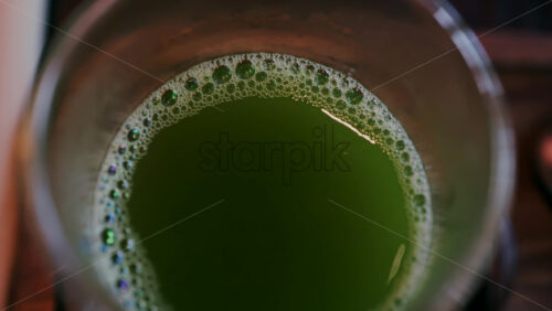 Close up of a glass of green tea on a wooden tray on a table - Starpik Stock