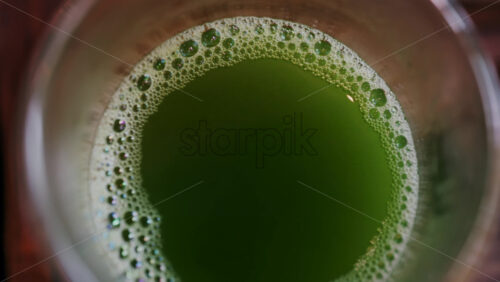 Close up of a glass of green tea on a wooden tray on a table - Starpik Stock