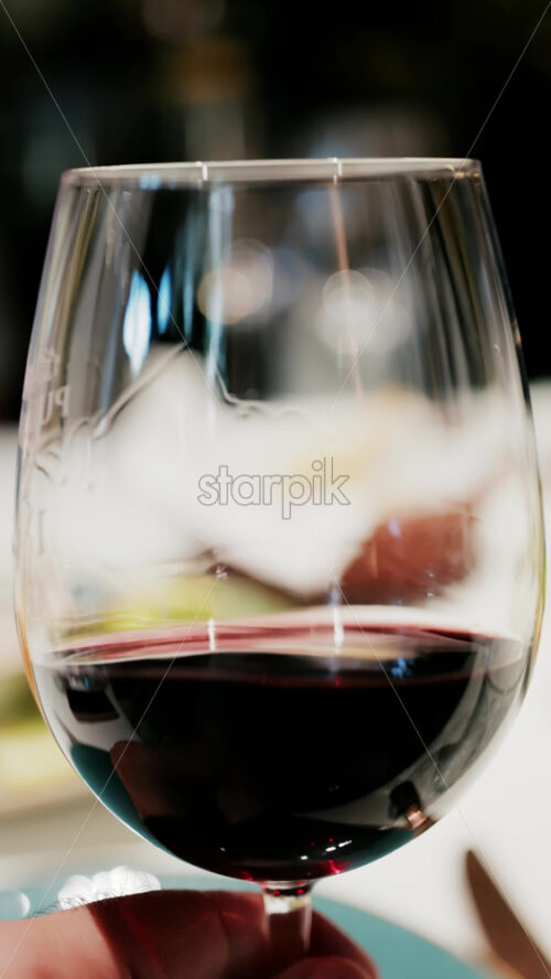 Close up of a glass of red wine being swirled showcasing the rich ruby colour. Vertical - Starpik Stock