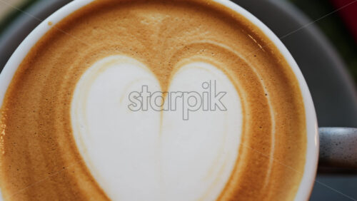 Close up of a heart made on a latte in a black cup - Starpik Stock