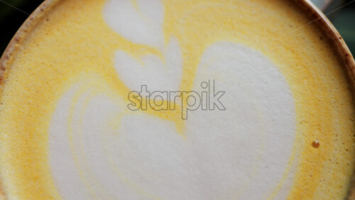 Close up of a heart-shaped latte art in golden turmeric coffee - Starpik Stock