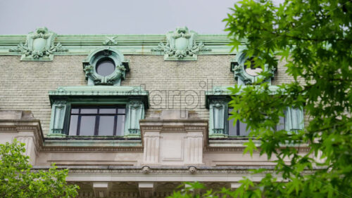 Close up of a historic building with an aged green copper roof and ornate round windows in central London, England - Starpik Stock