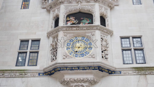 Close-up of a historic clock tower featuring golden Roman numerals and ornate stone carvings in London, England - Starpik Stock