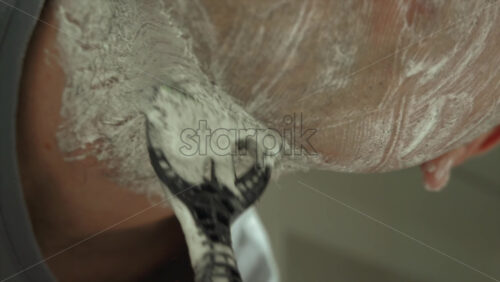 Close up of a man shaving his beard with a green and black razor - Starpik Stock
