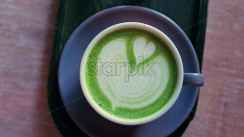 Close up of a matcha latte on a little green tray at a cafe - Starpik Stock