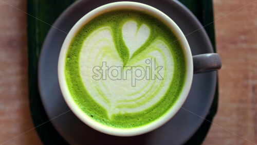 Close up of a matcha latte on a little green tray at a cafe - Starpik Stock