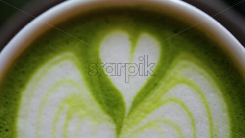 Close up of a matcha latte on a little green tray at a cafe - Starpik Stock
