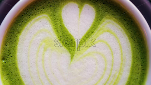 Close up of a matcha latte on a little green tray at a cafe - Starpik Stock