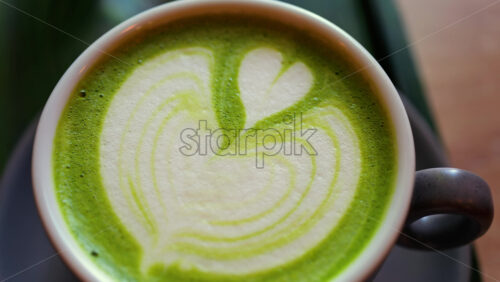 Close up of a matcha latte on a little green tray at a cafe - Starpik Stock