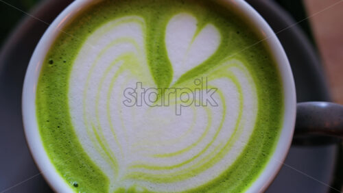 Close up of a matcha latte on a little green tray at a cafe - Starpik Stock
