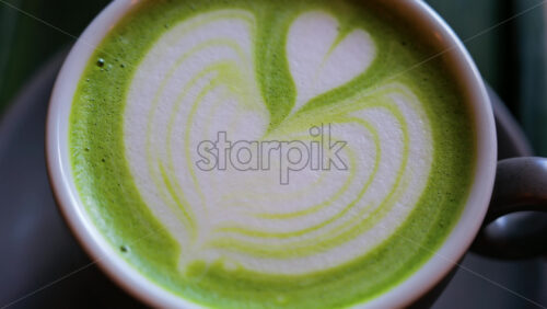 Close up of a matcha latte on a little green tray at a cafe - Starpik Stock