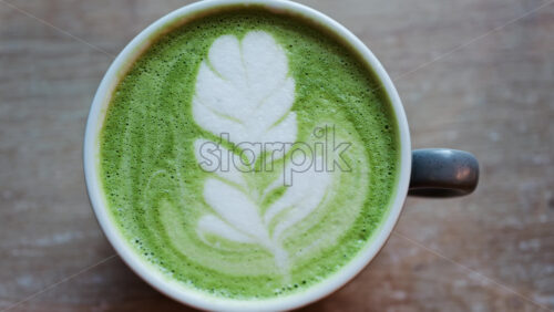 Close up of a matcha latte on a wooden table - Starpik Stock