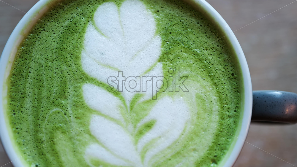 Close up of a matcha latte on a wooden table - Starpik Stock