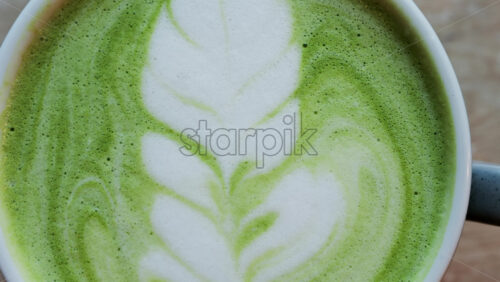 Close up of a matcha latte on a wooden table - Starpik Stock