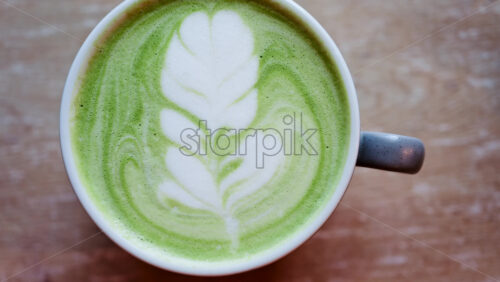 Close up of a matcha latte on a wooden table - Starpik Stock