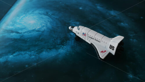 Close up of a miniature toy space shuttle placed on a blue cosmic galaxy backdrop - Starpik Stock