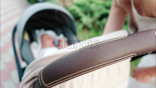 Close up of a mother placing a pacifier into a baby’s mouth while seated in a stroller - Starpik Stock