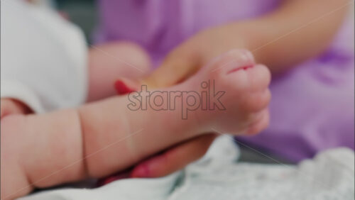 Close up of a parent’s hands massaging a baby’s hands and arms - Starpik Stock