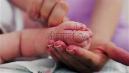 Close up of a parent’s hands massaging a baby’s hands and arms - Starpik Stock