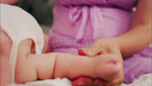 Close up of a parent’s hands massaging a baby’s hands and arms - Starpik Stock