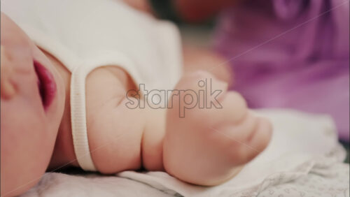 Close up of a parent’s hands massaging a baby’s hands and arms - Starpik Stock