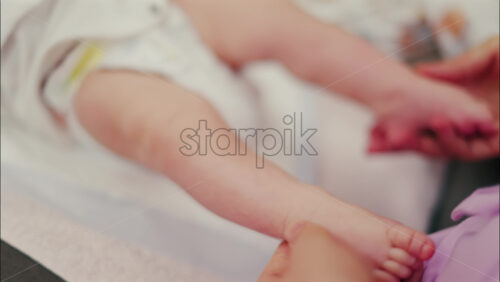 Close up of a parent’s hands massaging a baby’s legs - Starpik Stock