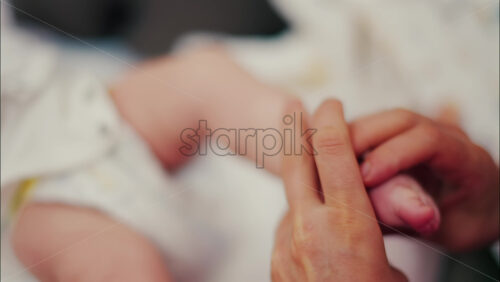 Close up of a parent’s hands massaging a baby’s legs - Starpik Stock