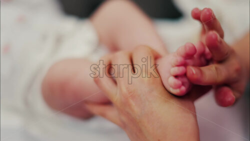 Close up of a parent’s hands massaging a baby’s legs - Starpik Stock