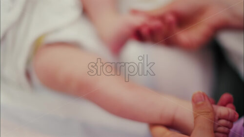 Close up of a parent’s hands massaging a baby’s legs - Starpik Stock