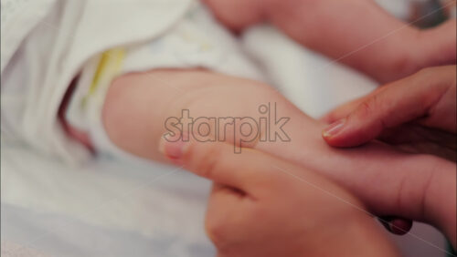 Close up of a parent’s hands massaging a baby’s legs - Starpik Stock