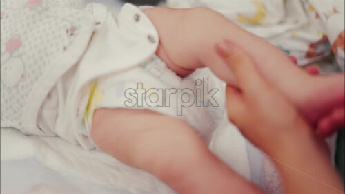 Close up of a parent’s hands massaging a baby’s legs - Starpik Stock
