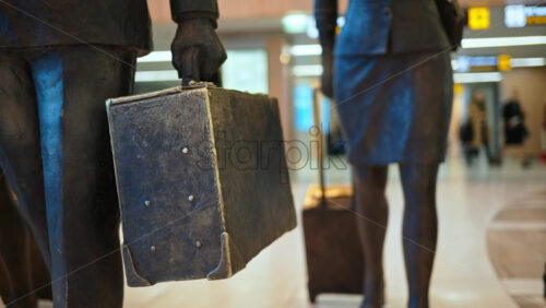 Close up of a pilot and two flight attendants holding luggages sculpture at the Chisinau International Airport in Moldova - Starpik Stock