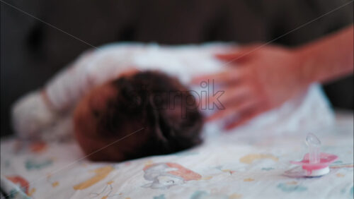Close up of a pink pacifier with a baby lying down and sleeping peacefully in the background - Starpik Stock