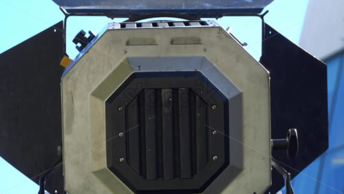 Close-up of a professional film light with set against a clear blue sky and a modern glass building - Starpik Stock