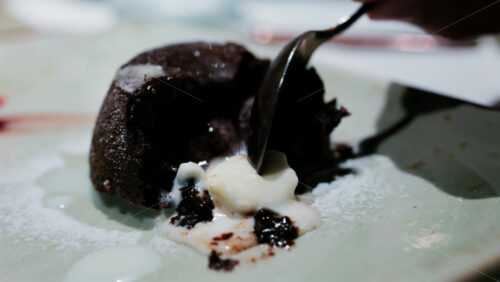 Close up of a rich chocolate lava cake with melted center served with vanilla ice cream - Starpik Stock