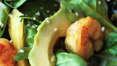Close up of a salad with spinach, avocado, shrimp, and peppers on a white plate - Starpik Stock
