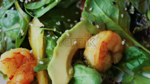 Close up of a salad with spinach, avocado, shrimp, and peppers on a white plate - Starpik Stock