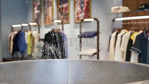 Close up of a small water sprinkler fountain inside a hipster clothing store - Starpik Stock