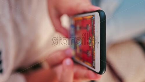 Close up of a smartphone with a cracked screen while a child plays a colourful mobile game. Vertical - Starpik Stock