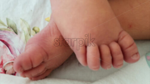 Close up of a the feet of a newborn baby resting on a white bedding with different patterns - Starpik Stock