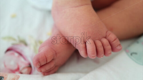 Close up of a the feet of a newborn baby resting on a white bedding with different patterns - Starpik Stock