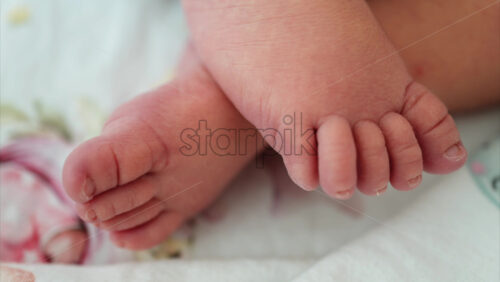 Close up of a the feet of a newborn baby resting on a white bedding with different patterns - Starpik Stock