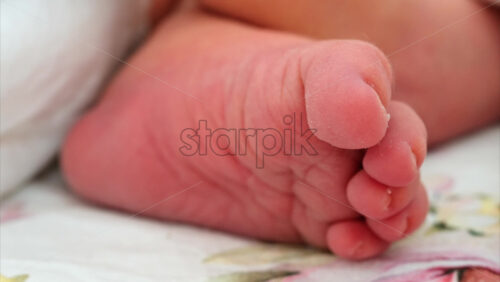 Close up of a the foot of a newborn baby resting on a white bedding with different patterns - Starpik Stock