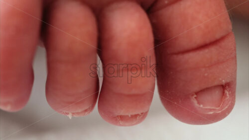 Close up of a the toes of a newborn baby resting on a white bedding with different patterns - Starpik Stock