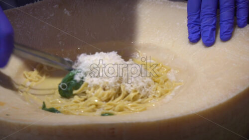 Close up of a waiter scraping parmesan cheese and adding it to the pasta in the wheel - Starpik Stock