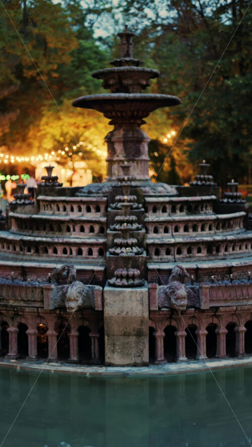 Close up of a water fountain in the Stephen the Great Central Park in Chisinau, Moldova with golden lights in the background. Vertical - Starpik Stock