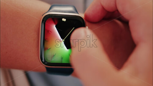 Close up of a woman changing the wallpaper on the smartwatch on her hand - Starpik Stock