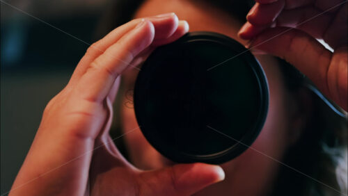 Close up of a woman rotating a camera lens filter near her face - Starpik Stock